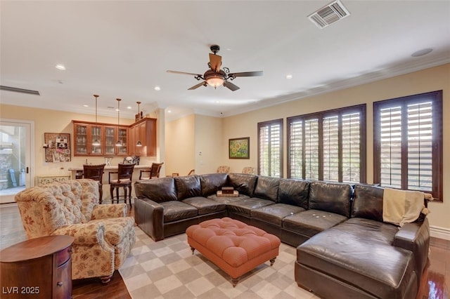 living area with ornamental molding, visible vents, and recessed lighting