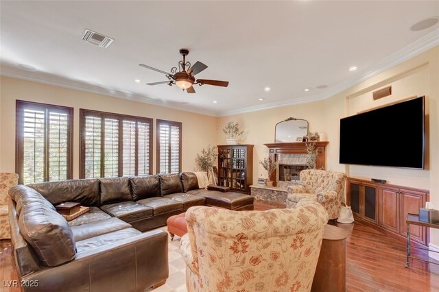 4450 Palisades Canyon Cir, Las Vegas, NV 89129 - living area with ceiling fan, light wood-style floors, a fireplace, recessed lighting, and crown molding