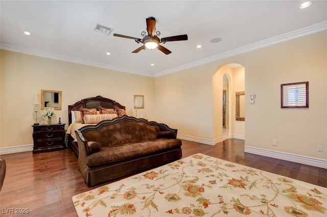 bedroom with dark wood-type flooring, arched walkways, crown molding, and baseboards