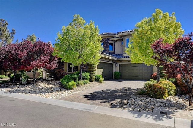 view of front of property featuring a garage, decorative driveway, a tiled roof, and stucco siding