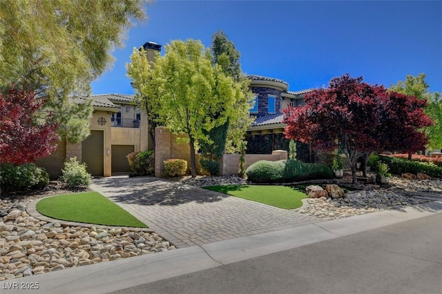 view of front of home featuring a garage, a tile roof, decorative driveway, and stucco siding