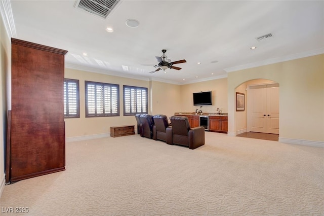 living room featuring beverage cooler, wet bar, ornamental molding, ceiling fan, and light colored carpet