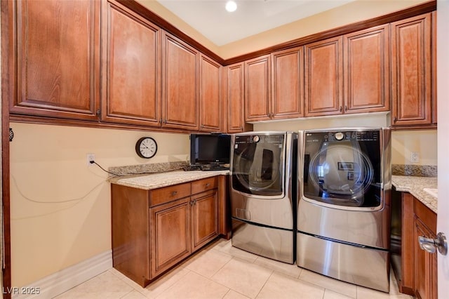 laundry room with light tile patterned floors, washing machine and dryer, baseboards, and cabinet space