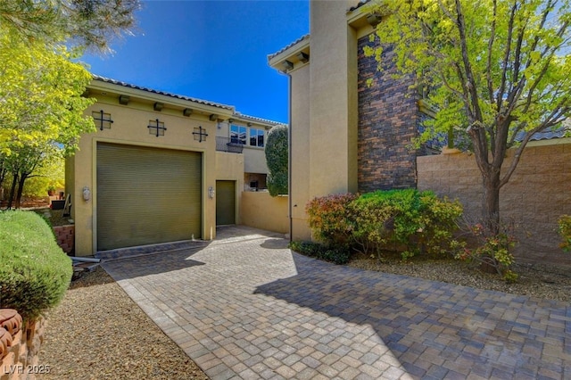 view of front facade featuring a tile roof, fence, a balcony, and stucco siding