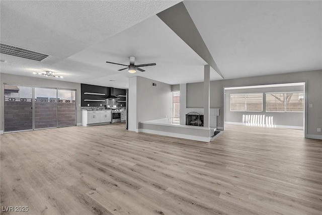 unfurnished living room featuring plenty of natural light, a textured ceiling, light hardwood / wood-style flooring, and a fireplace