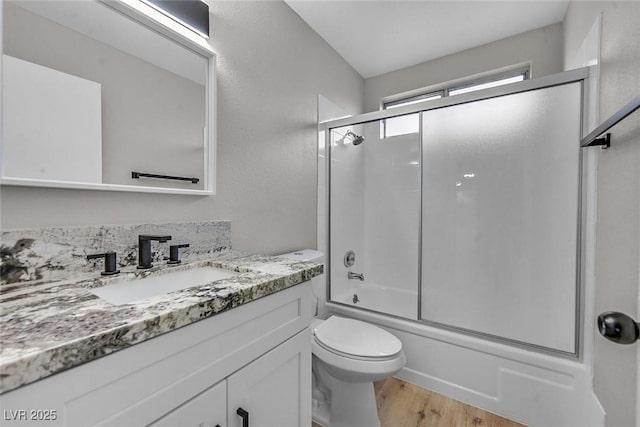 full bathroom featuring vanity, toilet, bath / shower combo with glass door, and wood-type flooring