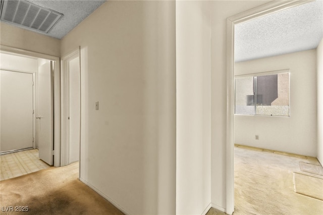 corridor with a textured ceiling and carpet flooring