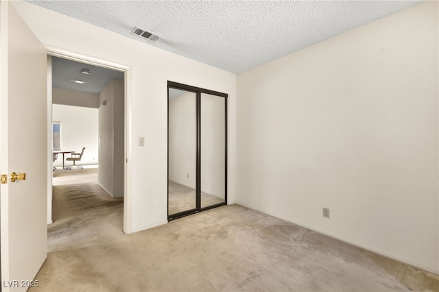 unfurnished bedroom featuring light carpet and a textured ceiling