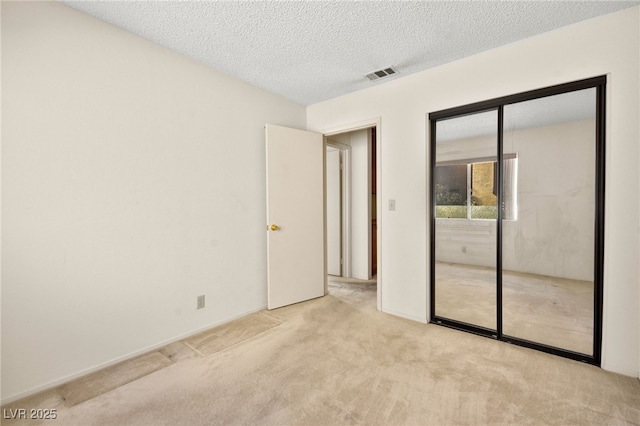 unfurnished bedroom featuring light carpet, a textured ceiling, and a closet