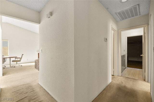 hall featuring a textured ceiling, lofted ceiling, and light carpet