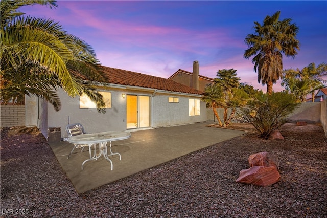 back house at dusk featuring a patio