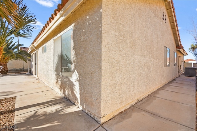 view of side of property featuring a patio and central AC