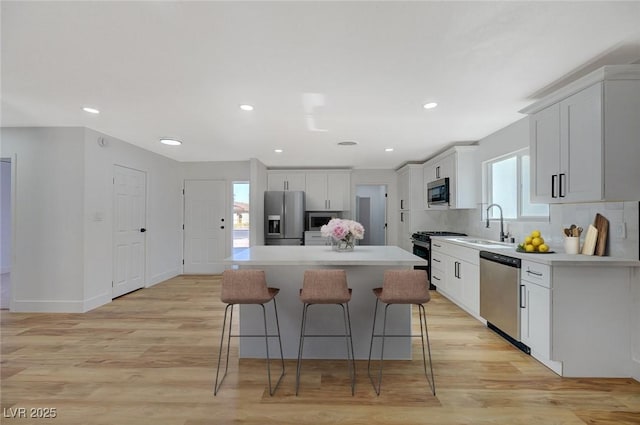 kitchen featuring a kitchen island, sink, white cabinets, backsplash, and stainless steel appliances