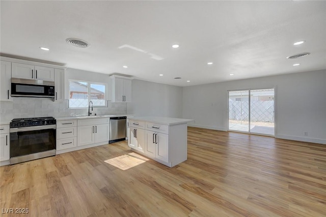 kitchen featuring sink, appliances with stainless steel finishes, tasteful backsplash, white cabinets, and light wood-type flooring