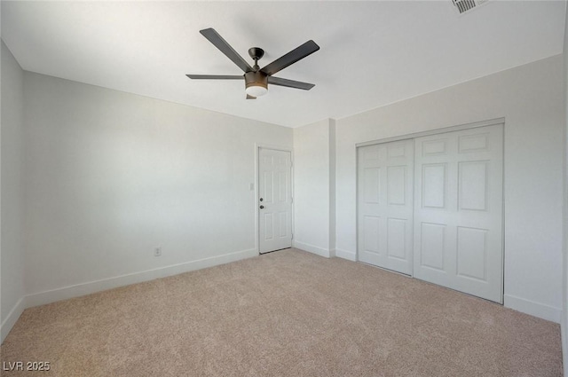 unfurnished bedroom featuring ceiling fan, a closet, and light carpet