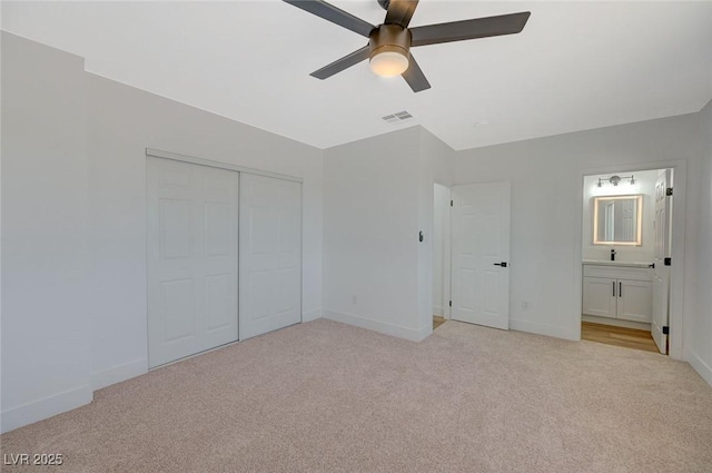 unfurnished bedroom with light carpet, ensuite bath, a closet, and ceiling fan