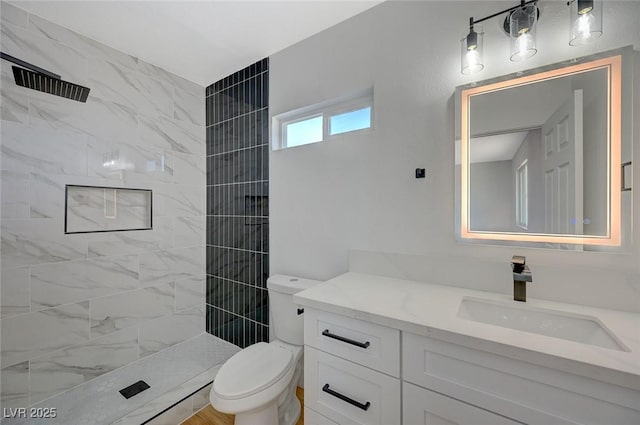 bathroom featuring vanity, toilet, and a tile shower