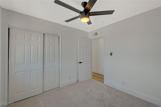 unfurnished bedroom featuring light carpet, a closet, and ceiling fan