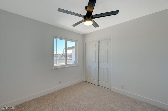 unfurnished bedroom with ceiling fan, light carpet, and a closet