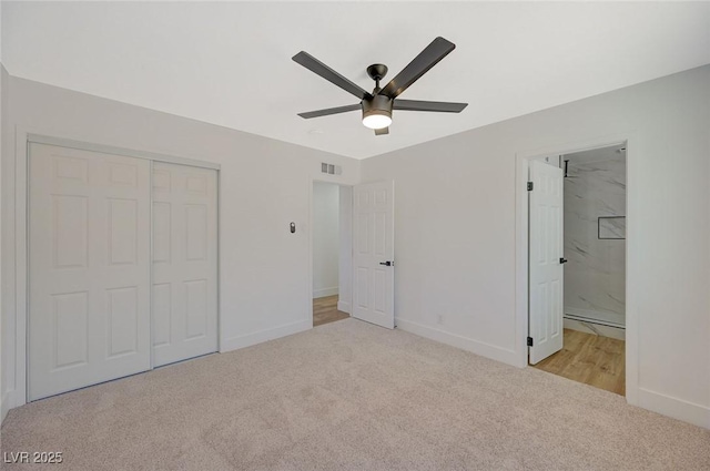 unfurnished bedroom with light carpet, ensuite bath, a closet, and ceiling fan