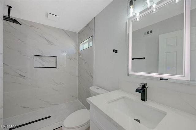 bathroom with vanity, toilet, and a tile shower