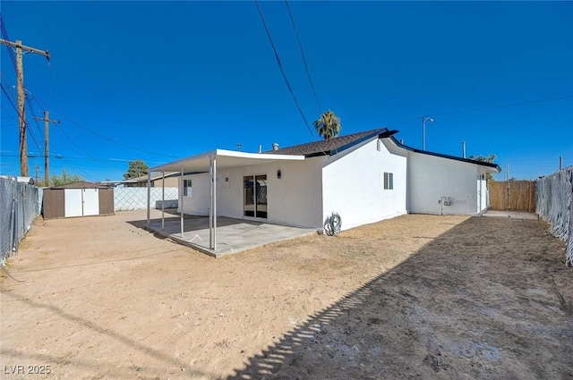 back of property featuring a patio and a shed