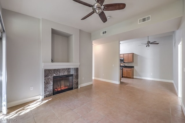 unfurnished living room featuring ceiling fan, light tile patterned floors, and a fireplace