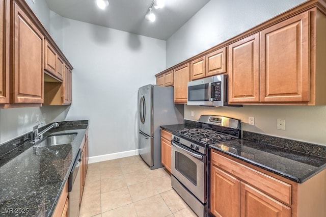 kitchen with sink, rail lighting, dark stone countertops, and stainless steel appliances