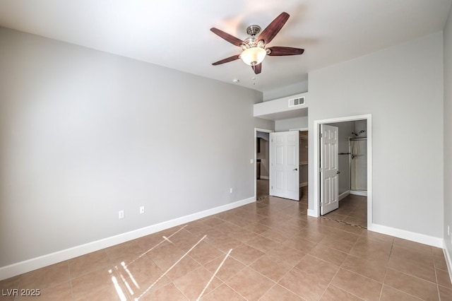 unfurnished bedroom featuring ceiling fan, light tile patterned floors, and ensuite bath