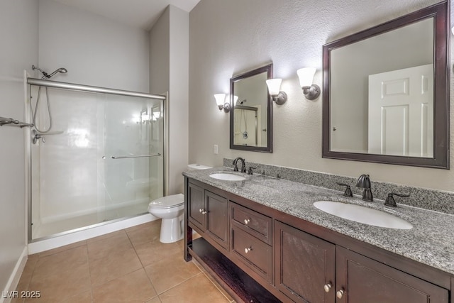 bathroom with an enclosed shower, vanity, toilet, and tile patterned flooring