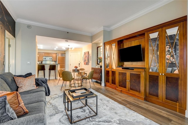 living room with light hardwood / wood-style flooring, crown molding, and a chandelier