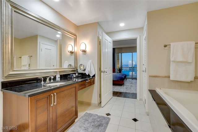 bathroom featuring tiled tub, vanity, and tile patterned flooring