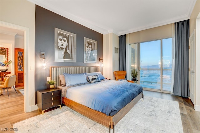 bedroom featuring access to exterior, a water view, crown molding, and hardwood / wood-style flooring