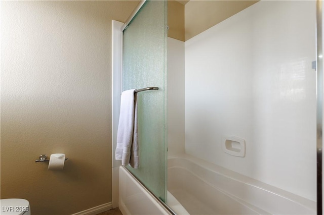 bathroom featuring toilet and combined bath / shower with glass door