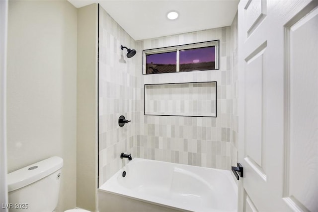 bathroom with tiled shower / bath combo and toilet