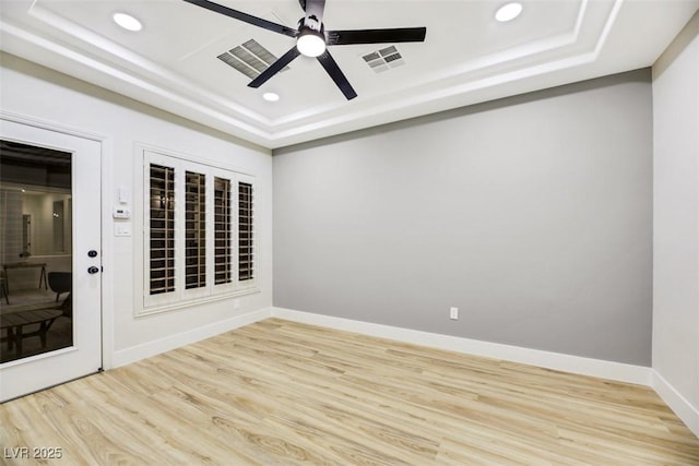 spare room featuring ceiling fan, light hardwood / wood-style flooring, and a tray ceiling