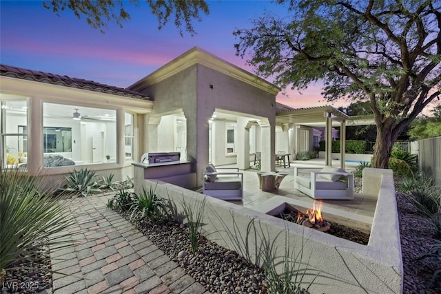 patio terrace at dusk featuring an outdoor fire pit and a pergola