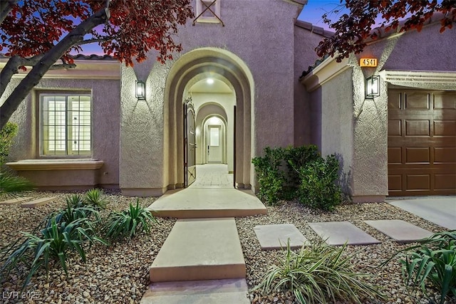 exterior entry at dusk featuring a garage