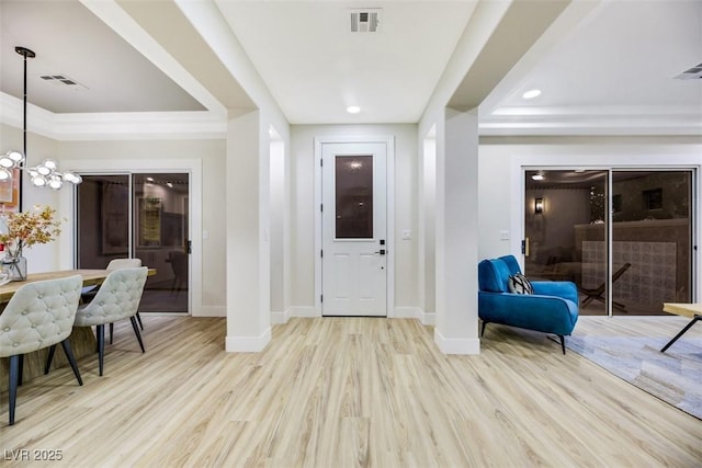 foyer with light hardwood / wood-style floors, a raised ceiling, and a notable chandelier