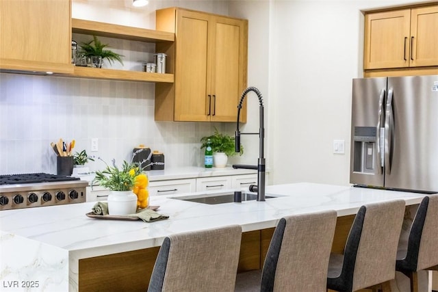 kitchen featuring a kitchen breakfast bar, sink, tasteful backsplash, stainless steel fridge with ice dispenser, and light stone counters