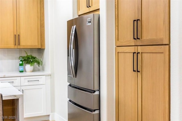 kitchen featuring white cabinets, decorative backsplash, and stainless steel refrigerator