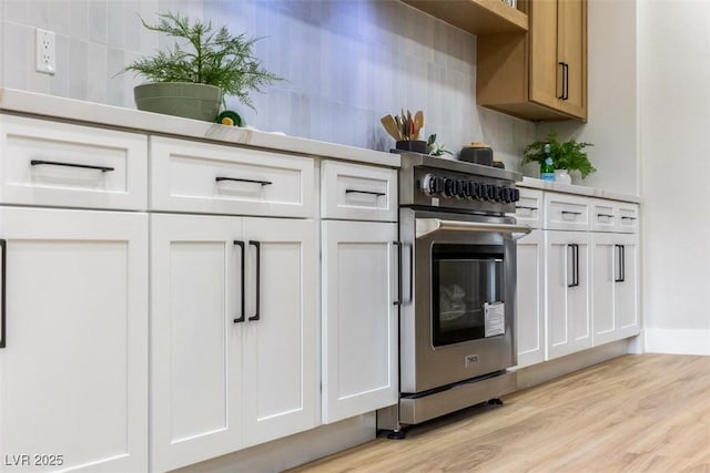 kitchen with high end stainless steel range oven, white cabinetry, and tasteful backsplash