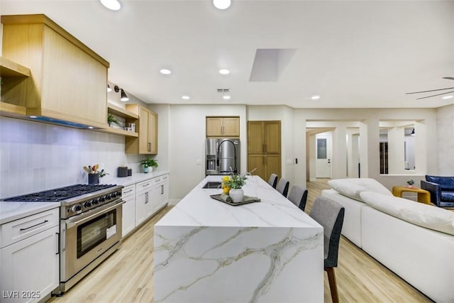 kitchen featuring sink, backsplash, high end stainless steel range, and a kitchen breakfast bar