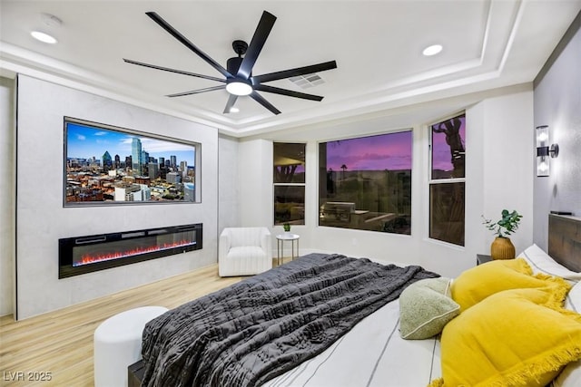 bedroom with hardwood / wood-style flooring, a tray ceiling, and ceiling fan