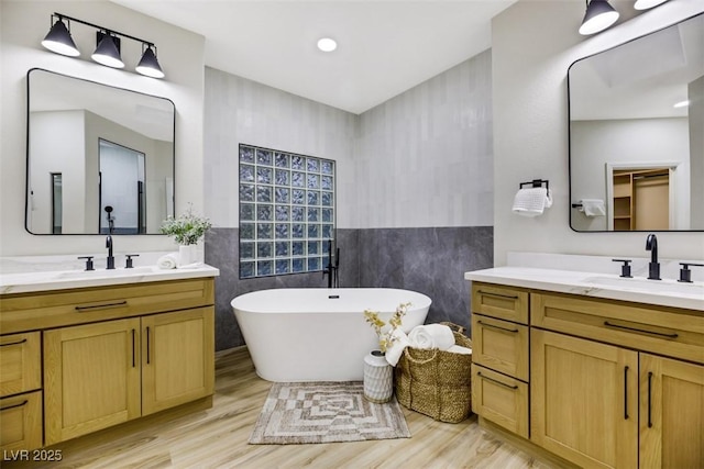 bathroom featuring vanity, wood-type flooring, tile walls, and a bathing tub