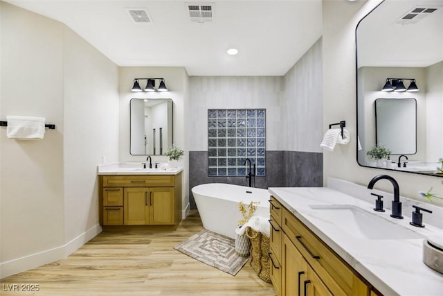 bathroom featuring hardwood / wood-style flooring, a washtub, and vanity