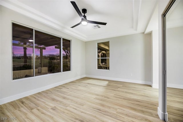 empty room featuring light hardwood / wood-style floors, a raised ceiling, and ceiling fan