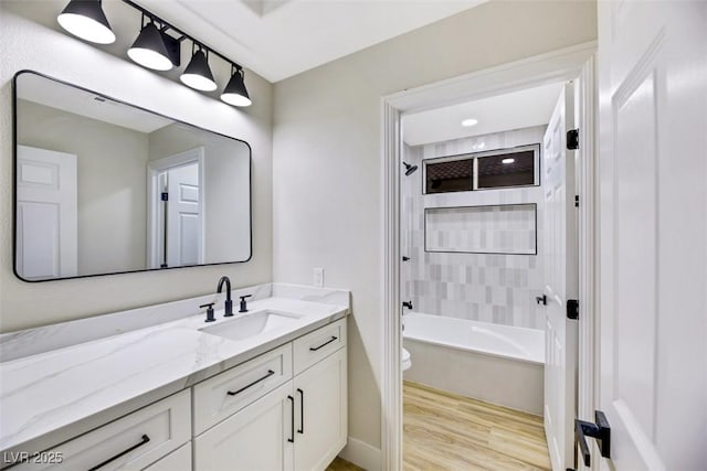 full bathroom featuring vanity, toilet, hardwood / wood-style floors, and tiled shower / bath combo