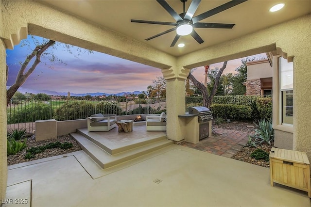 patio terrace at dusk with area for grilling, a grill, and ceiling fan