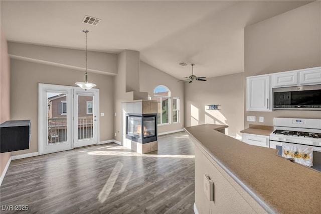 kitchen featuring pendant lighting, a tile fireplace, white cabinetry, dark hardwood / wood-style flooring, and white gas stove